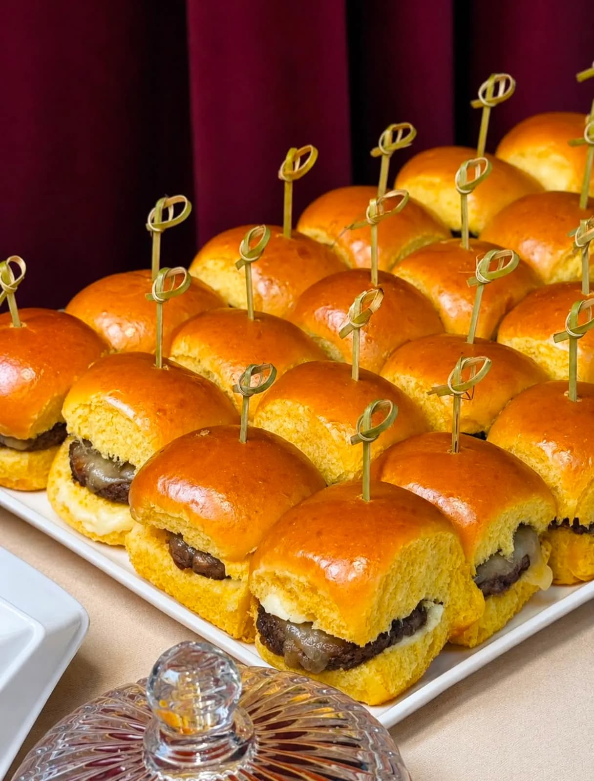 Bandeja de mini-hambúrgueres em pão brioche espetados com palito de bambu